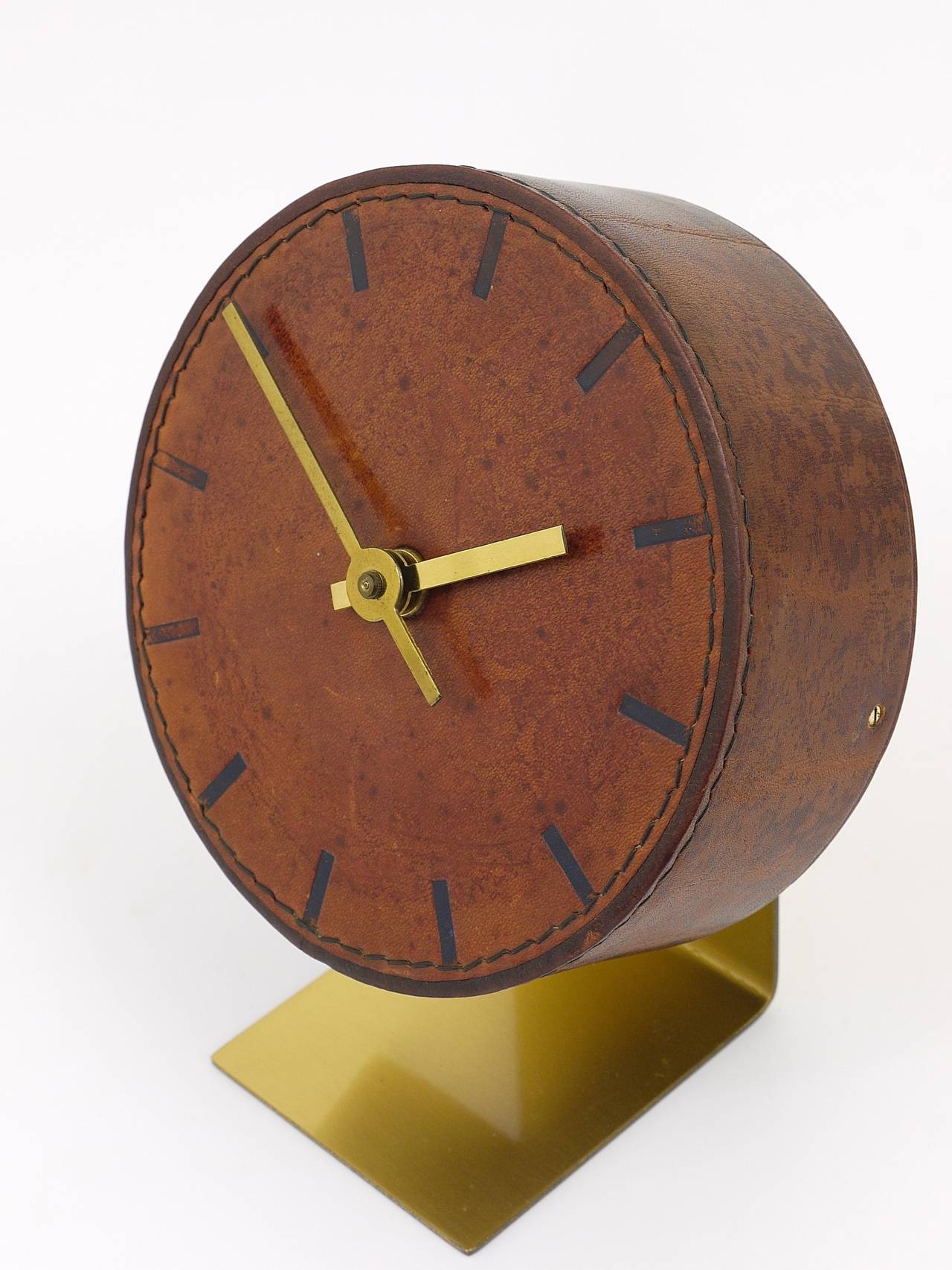 A beautiful leather and brass clock, designed and executed by Carl Aubock, Vienna, 1950s. An amazing straight-lined clock, has a leather wrapped clocks face and embossed marks for each hour. Battery-operated movement. Very good condition, charming