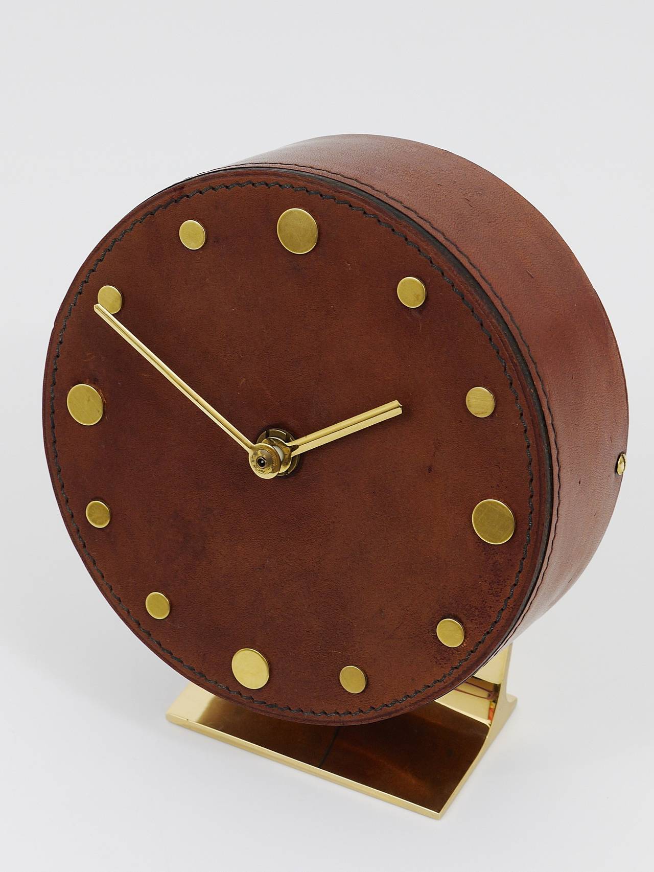 A beautiful leather and brass clock, designed and executed by Carl Aubock, Vienna, 1950s. An amazing straight-lined clock, has a leather wrapped clocks face and brass dots for each hour. Battery-operated movement. Very good condition, charming