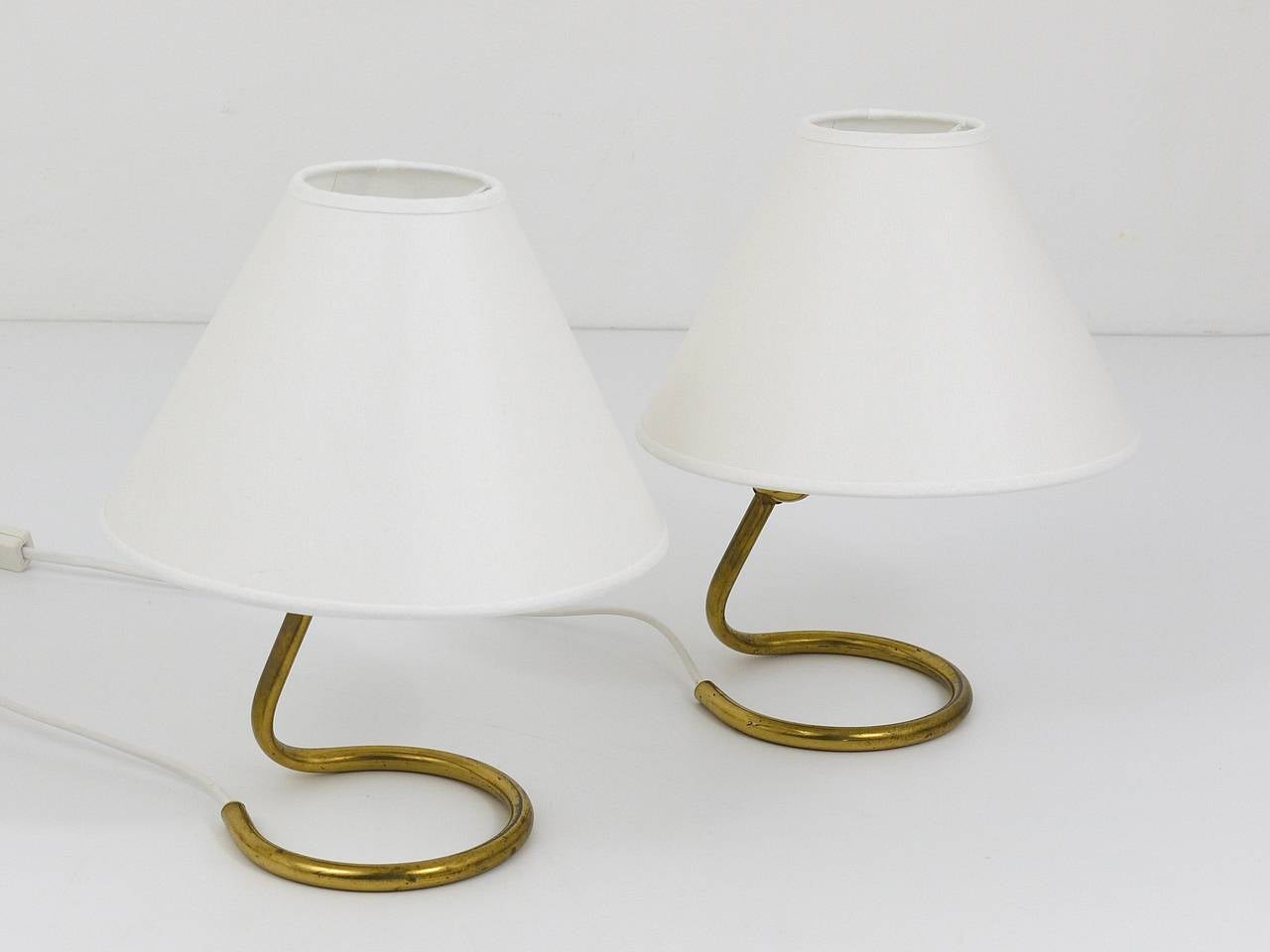 A beautiful pair of Austrian table lights, executed by Kalmar Vienna in the 1950s. Brass bases with white cone lampshades. In very good condition, nice patina on the brass. A very charming pair of lights.