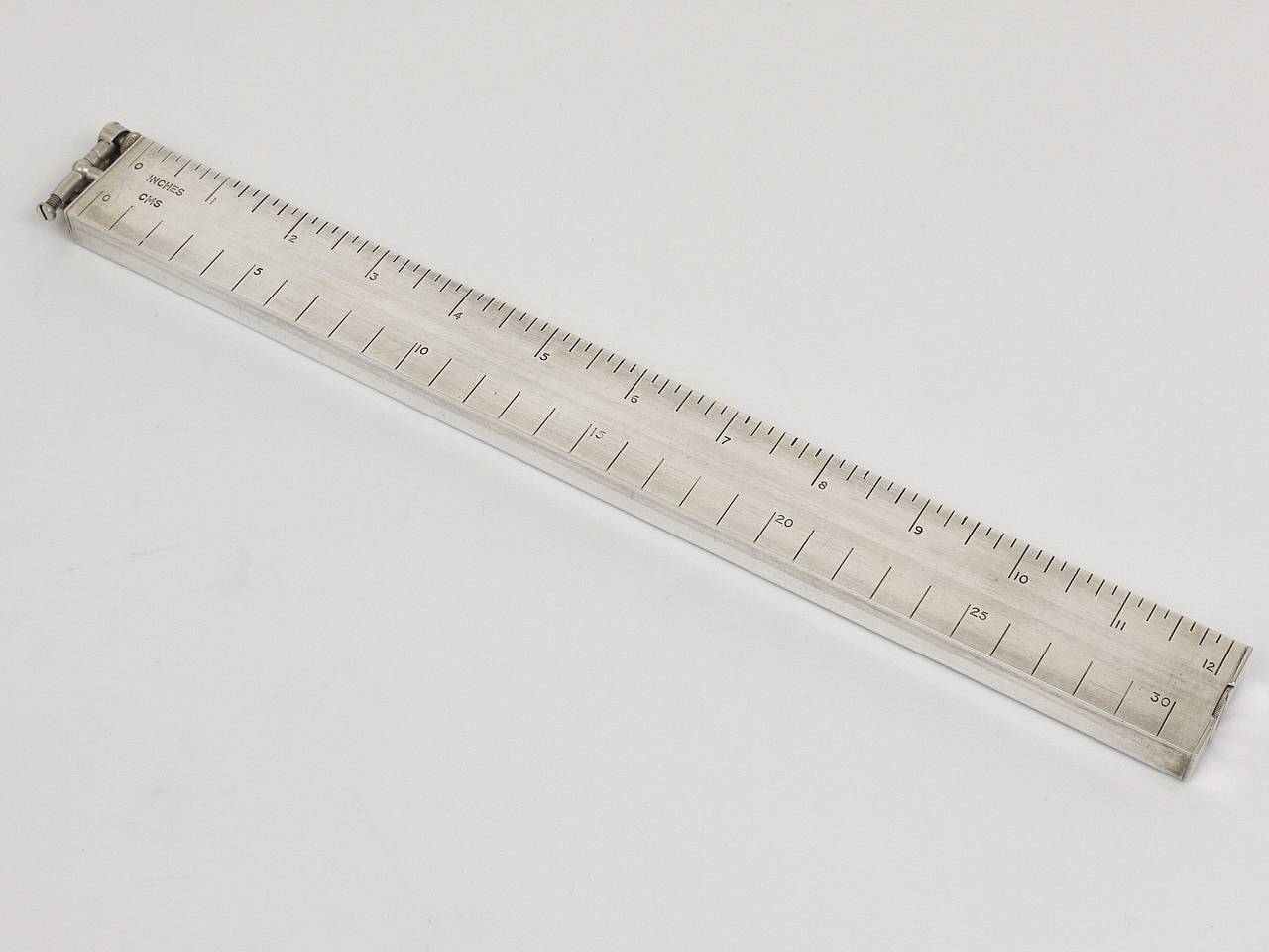 An unusual and rare silver-plated desk lighter in the shape of a ruler, with both inches and centimeter markings engraved. Made by Alfred Dunhill, England, 1950s. Works perfectly, in very good condition.  An ultimate desk accessory. Stamped