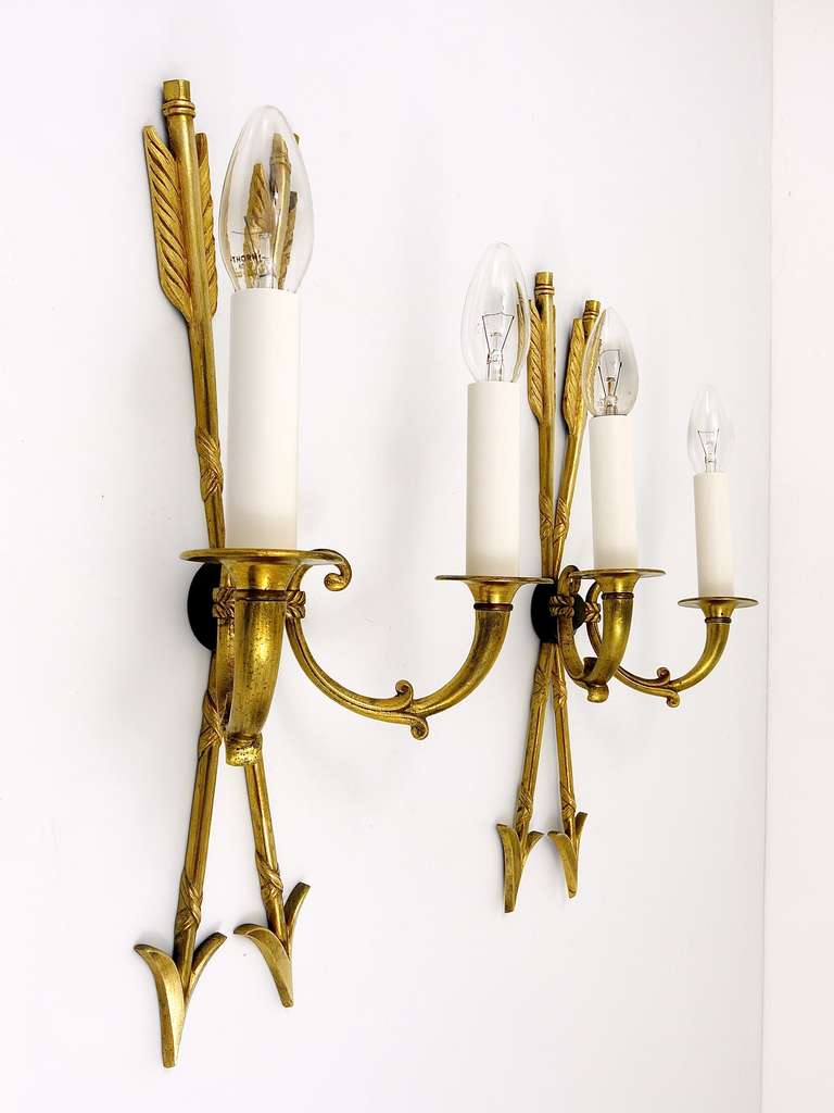 A beautiful pair of golden Empire style wall sconces with crossed arrows, in the manner of Maison Charles, made in France in the 1960s.  Recently rewired and in excellent condition. Very sophisticated lights. Height 17 1/2 inch, depth 5 inch.