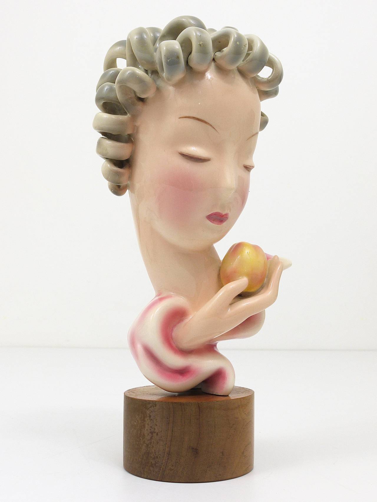 A beautiful and rare Art Deco porcelain bust on a wooden base. Eve with apple, model #6774, designed by Rudolph Knorlein, executed in the 1930s by Friedrich Goldscheider Vienna, Austria. Marked and numbered. In excellent condition.