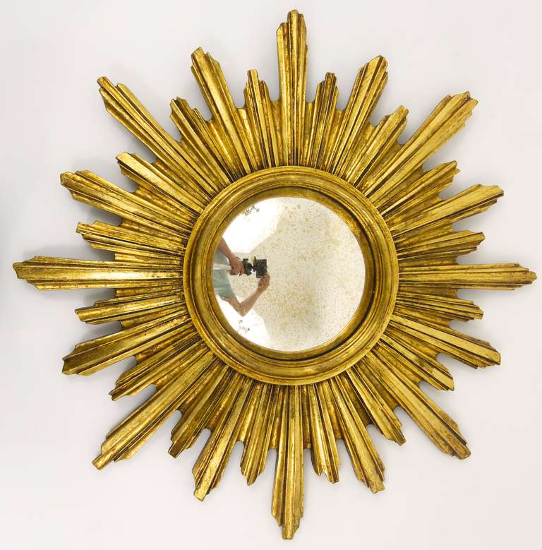 A very beautiful and decorative sunburst/starburst gilt wall mirror with convex mirror glass from France, dated around 1950. A very beautiful and decorative object in very good condition, with charming signs of age on the mirror glass. Diameter 21
