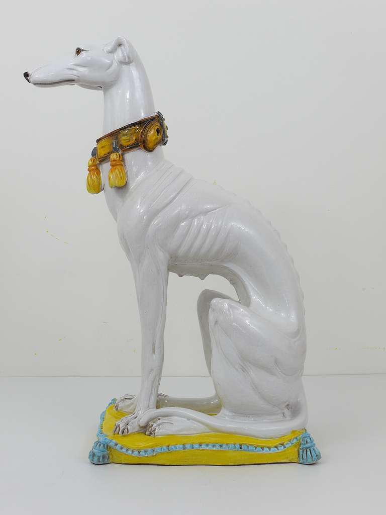 Very beautiful and detailed ceramic statue of a white greyhound with a decorative collar, seated on a tasseled cushion. Made in Italy, dated around 1950. Excellent condition. 26