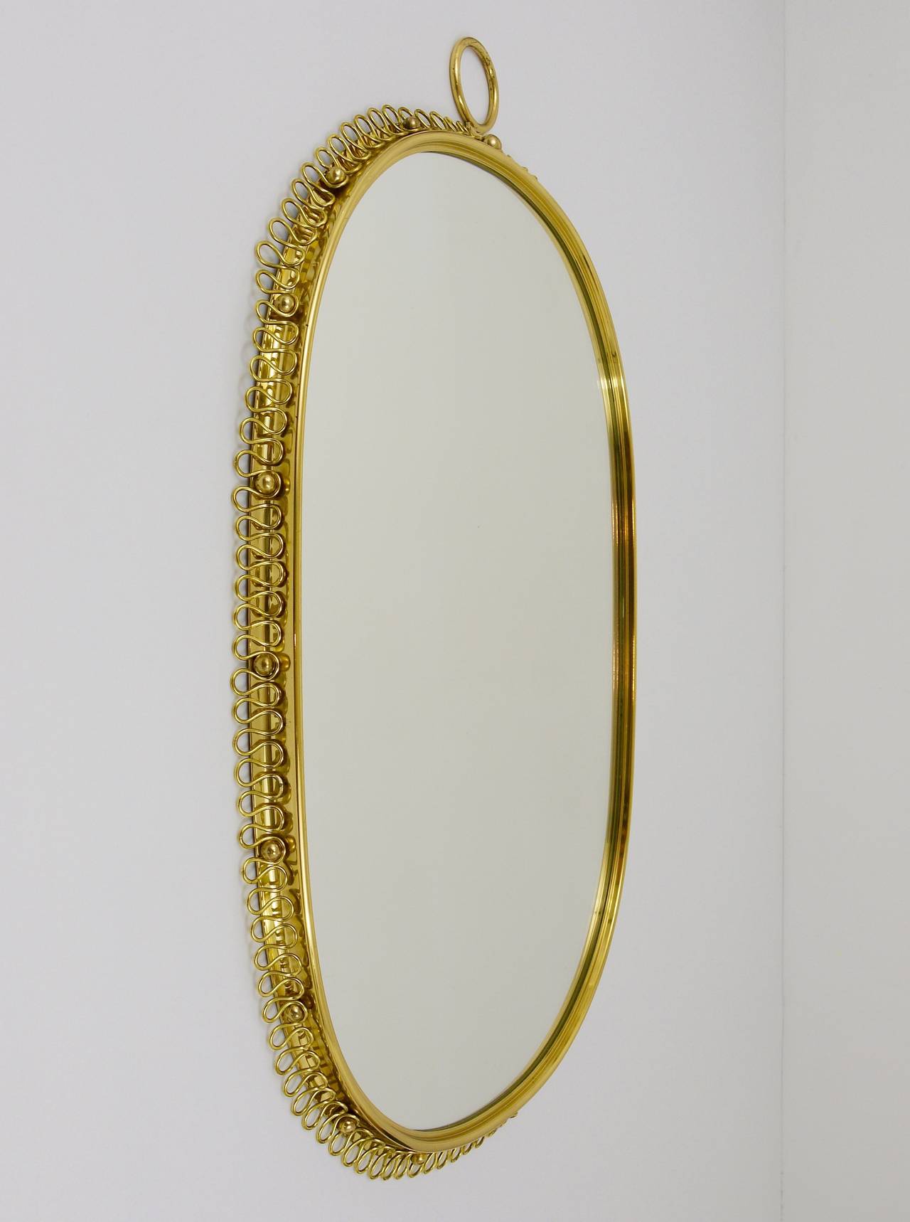 A beautiful Viennese mirror with a nice brass loop frame and a decorative brass ring from the 1950s. Designed by Josef Frank. In excellent condition with marginal patina.