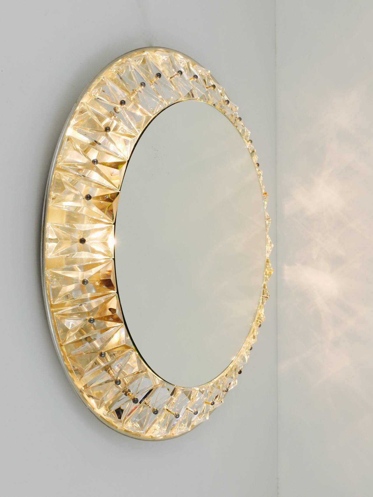 A beautiful round modernist wall mirror with a frame of huge faceted crystals. Designed and executed by Bakalowits & Sohne in the 1950s. Excellent quality. The mirror takes up to 8 bulbs; the crystals are 4