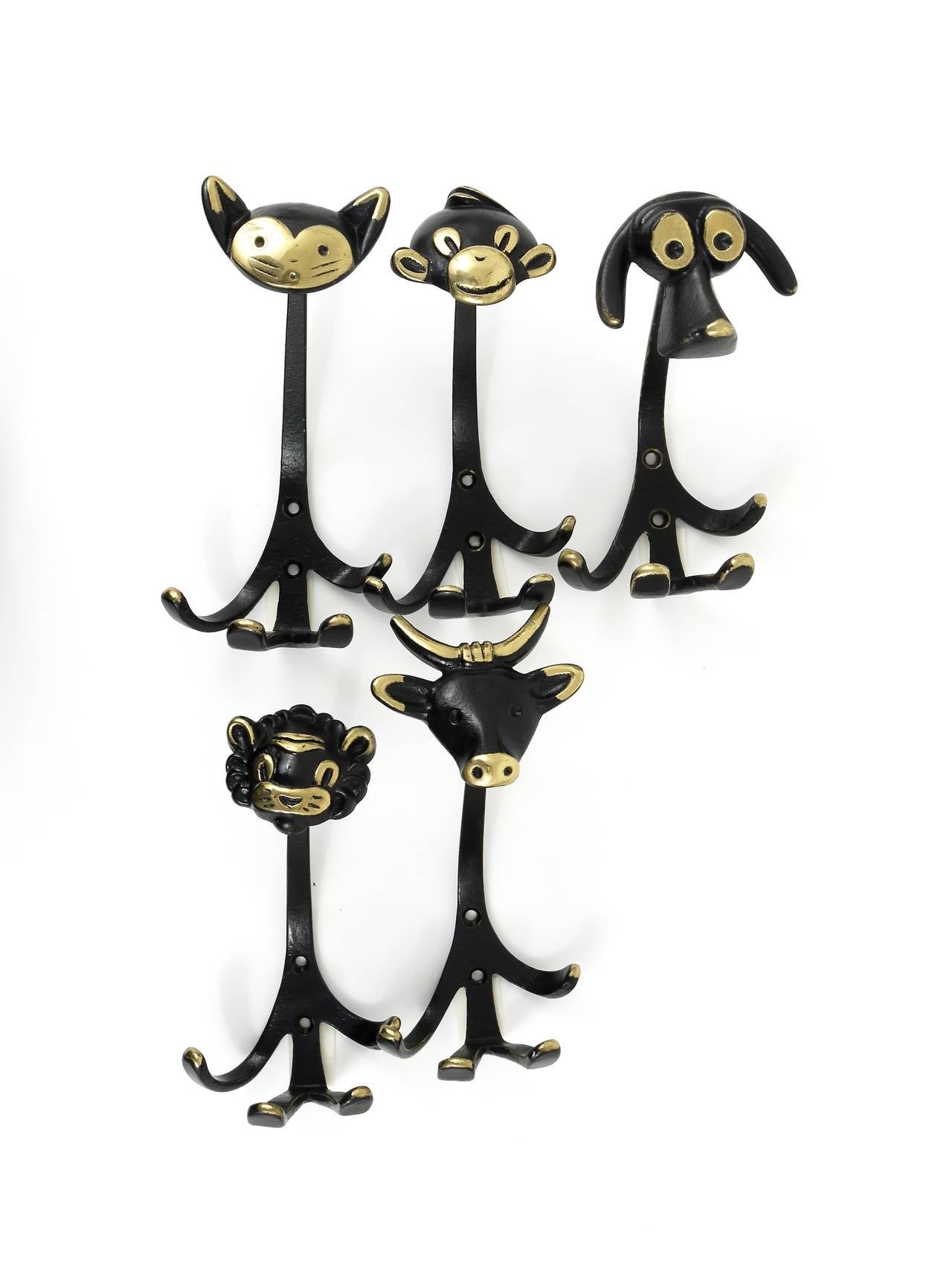 A set of five Austrian modernist brass wall coat hooks, displaying a dog, a cow, a lion, a cat and a monkey. A very humorous design by Walter Bosse, executed by Hertha Baller Austria in the 1950s. Made of black finished brass. In very good condition