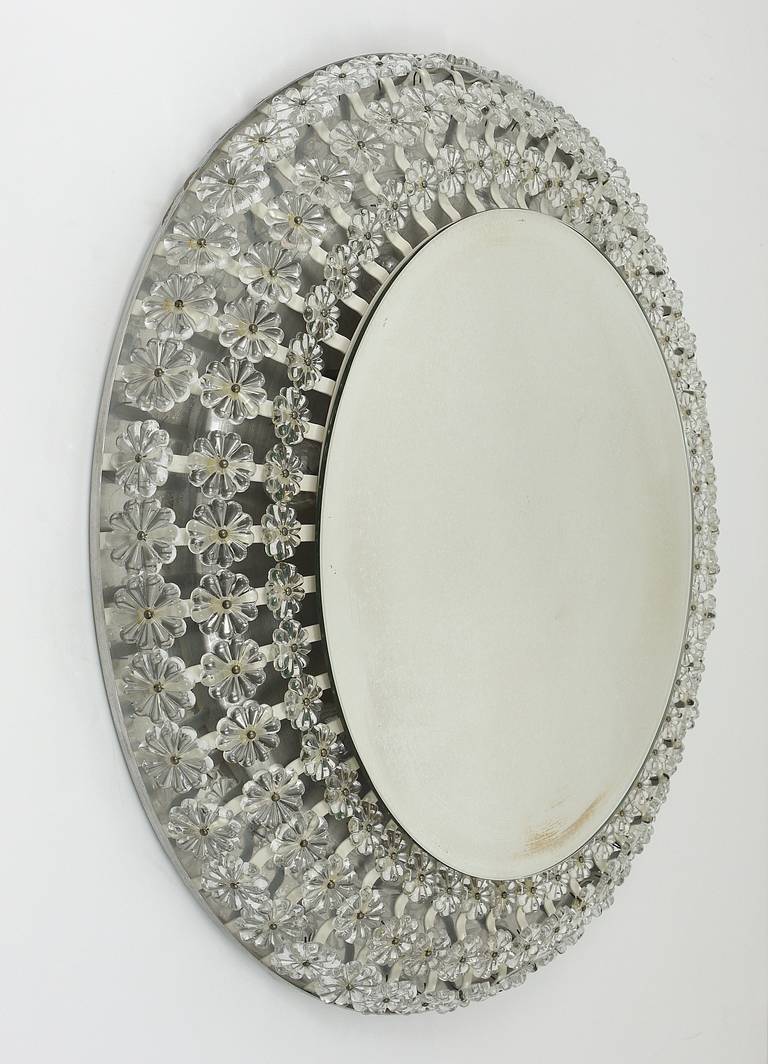 A beautiful, 28 in diameter, round modernist wall mirror with background illumination, surrounded by lots of charming crystal glass blossoms (not plastic). Designed by Emil Stejnar in the 1950s for the Viennese espresso Ohne Pause. Executed by