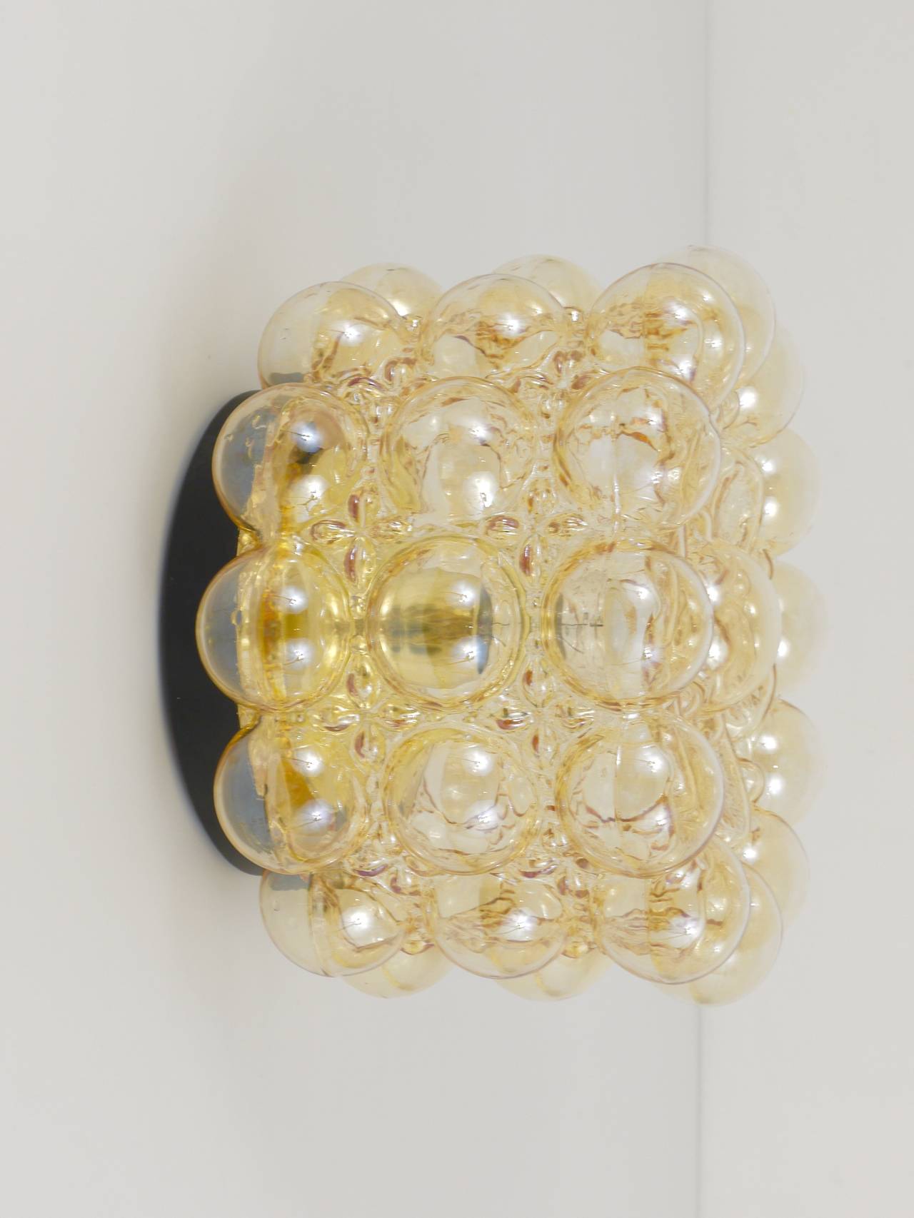 A beautiful bubble glass lamp in very good condition. To use as a flush mount or sconce / wall lamp. Designed by Helena Tynell, executed in the 1960s by Glashutte Limburg, Germany. Bubble glass lampshade in amber with a nice light golden mirroring