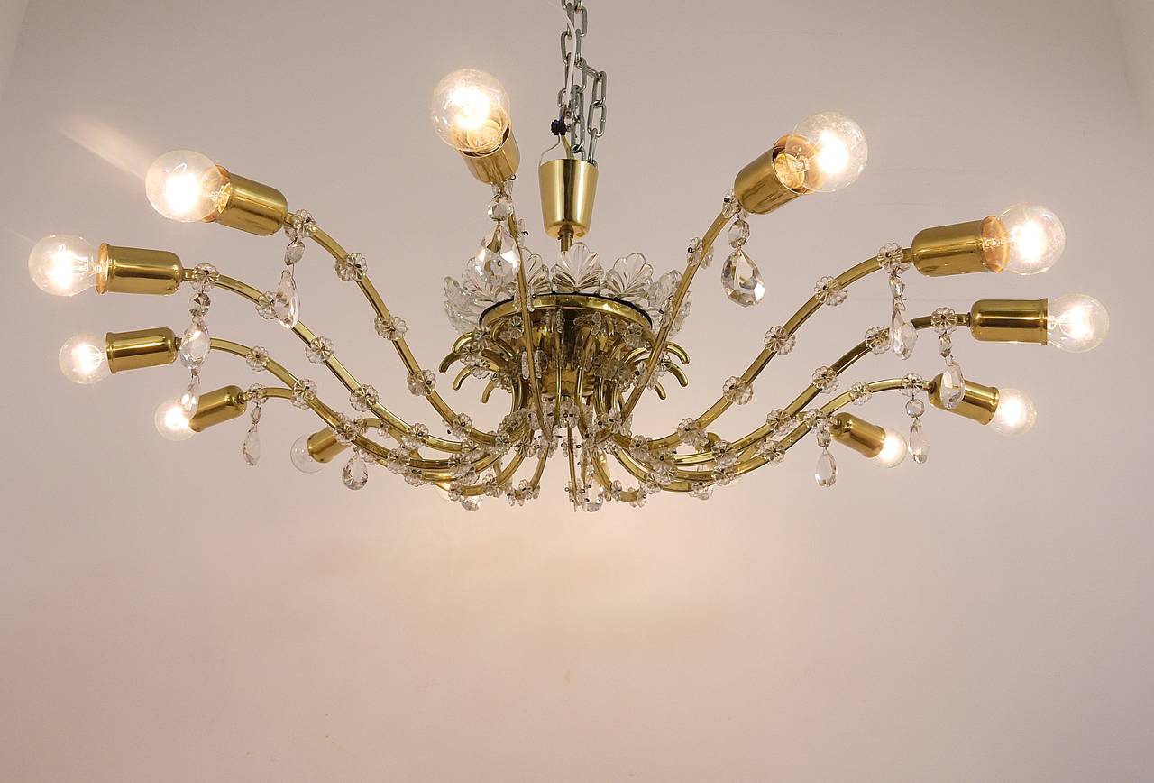 A beautiful and large brass and crystal glass chandelier, executed by Lobmeyr Vienna in the 1950s. The chandelier has 14 arms and nice floral glass details. In good condition with nice patina on the brass. Measures: Diameter 44 in, the total height