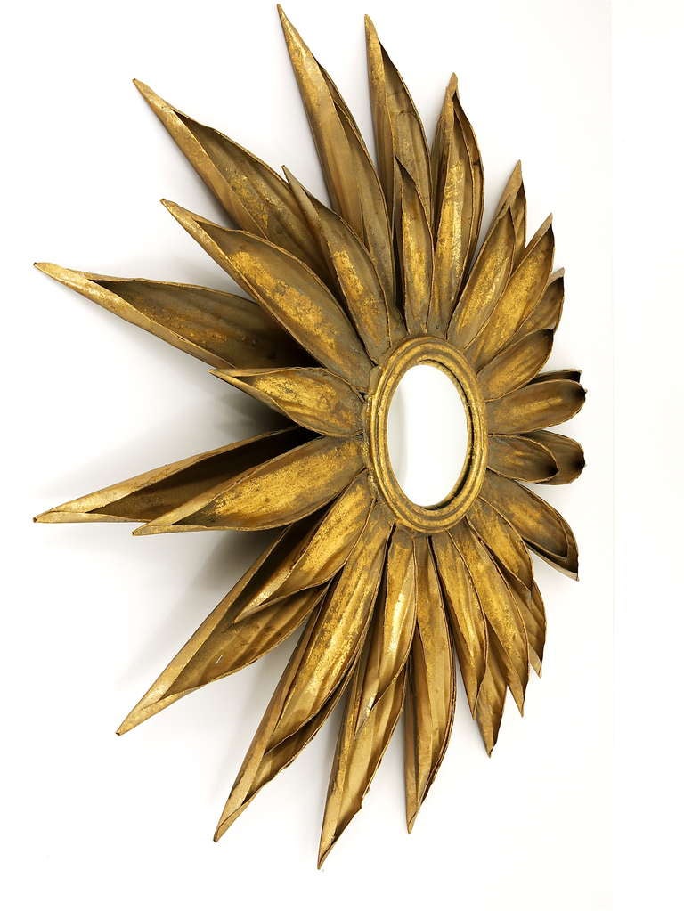 An unique piece. A big and beautiful Sunburst Mirror, made in France in the 1950s. In the shape of a blossom, made of gilded metal with a convex mirror glass. Total diameter 35 inches, diameter of the mirror is 6 inches;.  Good condition with nice