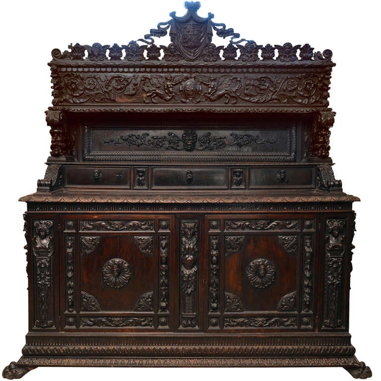 A carved walnut italian credenza.  The upper part with three drawers and with carved motives including two coat of armor.  The lower section with tho doors interposed by three female arms.  On paw front and bracket rear feet.  Italy, Tuscany, Siena
