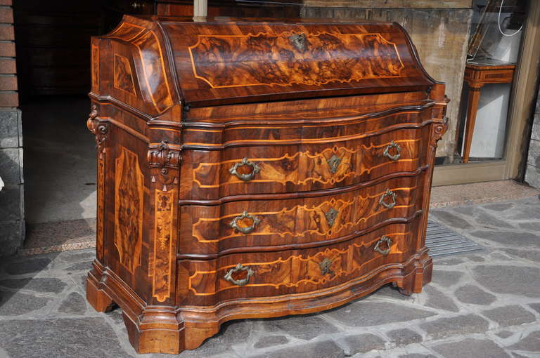 A very elegant  rare italian bureau, overall veneered and inlaid with walnut and burl walnut; the moulded top over three drawers.
The sides are decorated with carved motives.
The upper door opening to six little drawers.
Italy, Verona First half