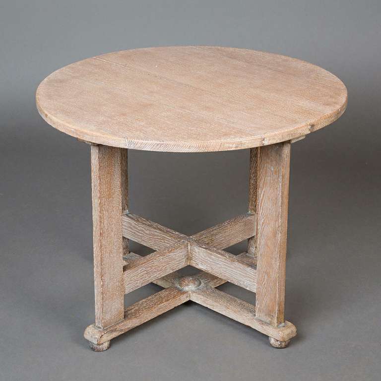 A 1930s limed oak occasional table by Hypnos Cabinets and retailed by Bowman Bros., the circular top raised on four rectangular section legs united by a double cross frame stretcher on bun feet, labels to underside