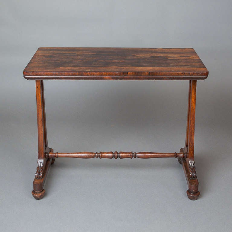 An early Victorian rectangular rosewood side table, raised on two pairs of square-shaped columns with leaf carved terminals, on splay feet and castors