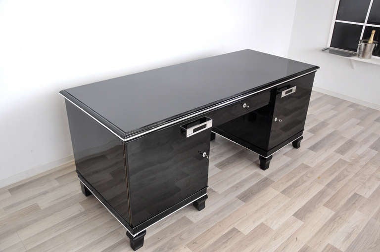 High gloss black  desk with eight beautifully carved French feet, a piano lacquer paintjob and a hand polished finish. A unique masterpiece with fine details like chrome bars and handles. It features lockable doors and four narrow drawers on the