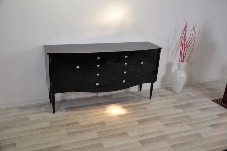 Art Deco sideboard from france with filigree legs and a curved body. The tabletop features hand polished piano lacquer and walnut wood details. On the front you will find chrome knobs on the two doors and the 4 large drawers. The drawers are