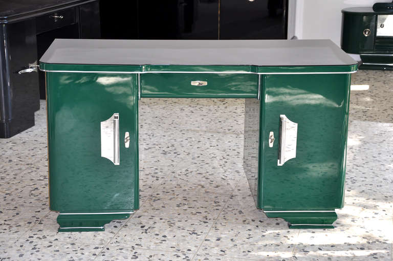 Art Deco desk from switzerland with a unique paintjob.It features a black cut glass top plate and a jaguar racing green paintjob. The design is complemented by big chrome handles on the front doors. The table is finished all around a can be used in