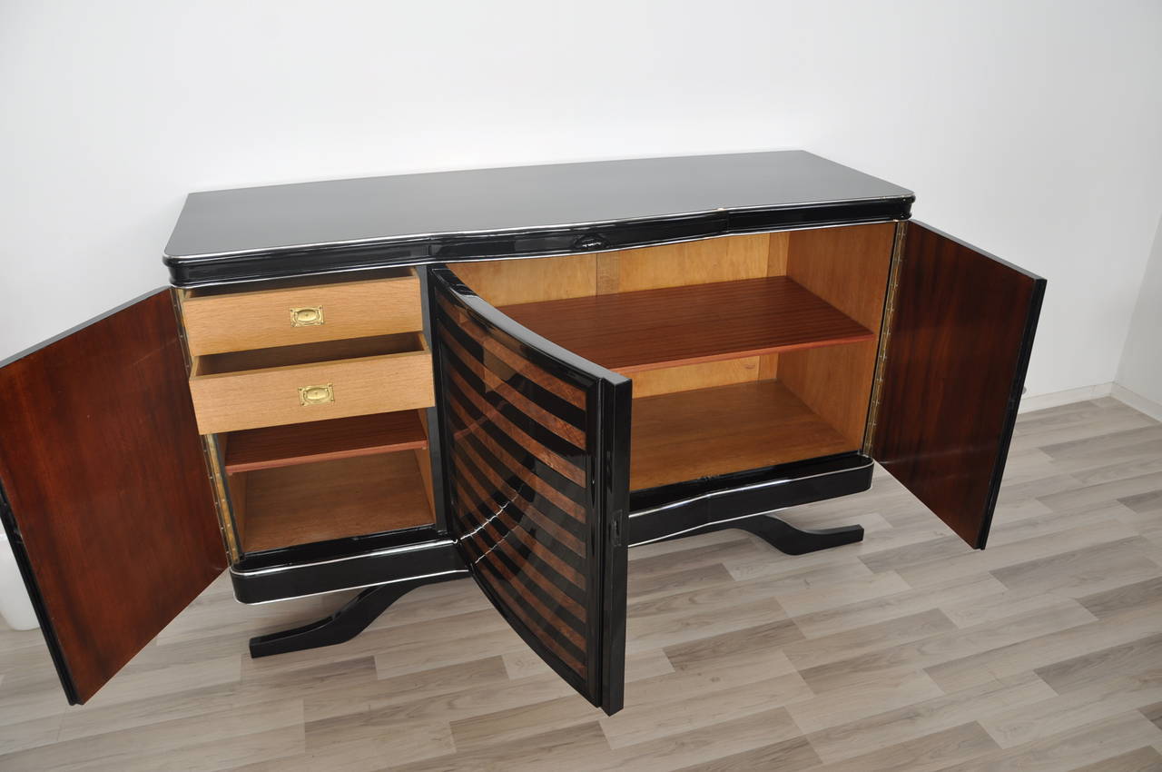 Rare Art Deco sideboard with a banded dark walnut veneer. The simple but elegant body shape is refined with big and luxurious chrome handles and hand polished black lacquer with a mirror finish. Single piece restored in our manufactory in Senden,