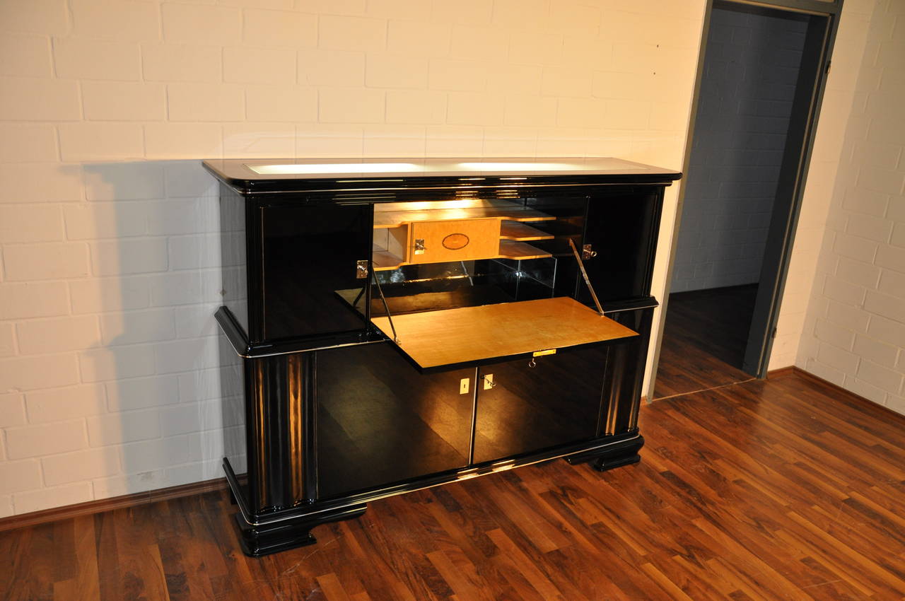 Elegant Art Deco Secretary from France around 1930. With an illuminated top plate made of milk glass, french feet and an all around high gloss black finish. The interior features small storage compartmens and shelves. The inside backpanel is