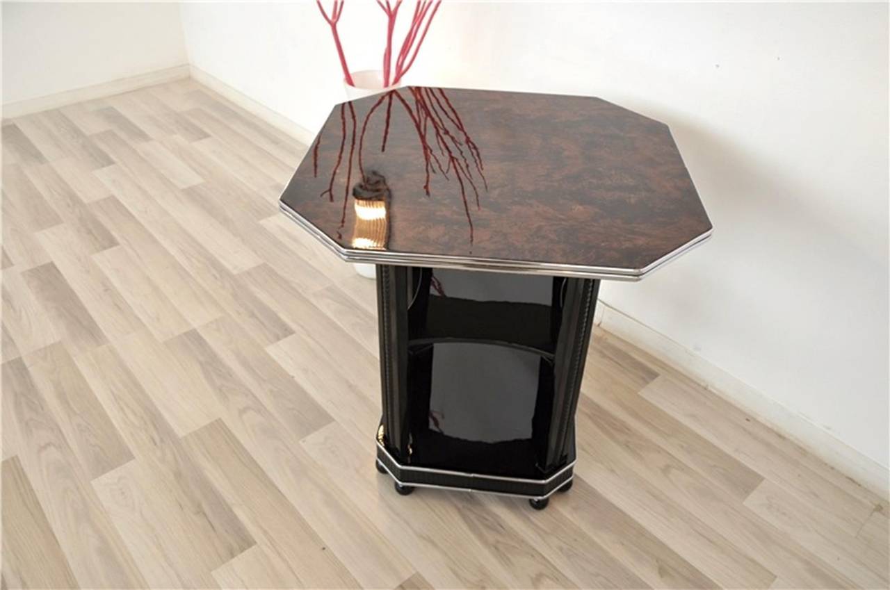 Rare Art Deco side table with a amboyna wood veneer and beautifully carved details on the legs. A special piece of furniture for every room. It features a octagonal tabletop with a unique grain and color tone. The lower part consists of two shelves
