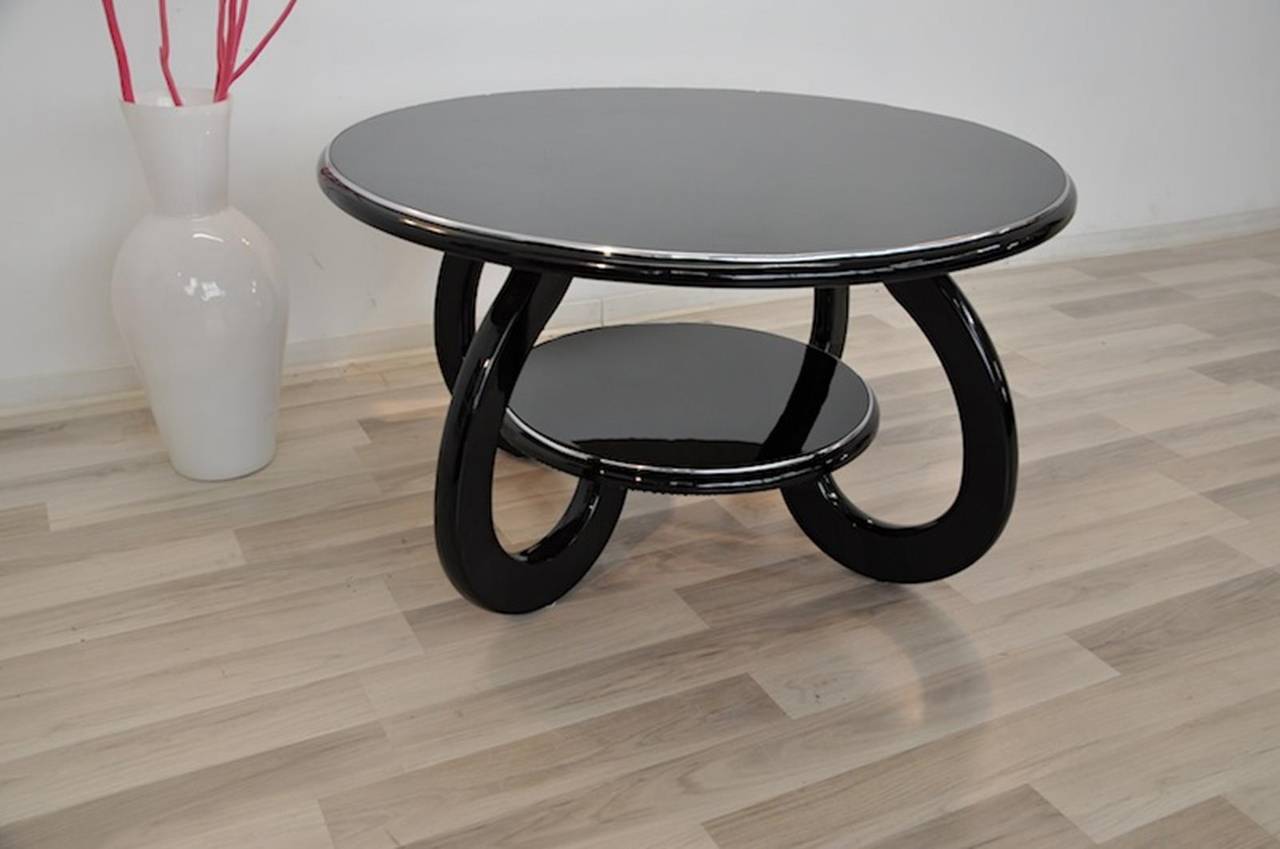 Wonderful Art Deco coffee table with a two round shelves and beautifully curved legs. Refined with chrome bars and our signature black piano lacquer. The table got restored by hand in our manufactory in Senden, Germany with only high quality