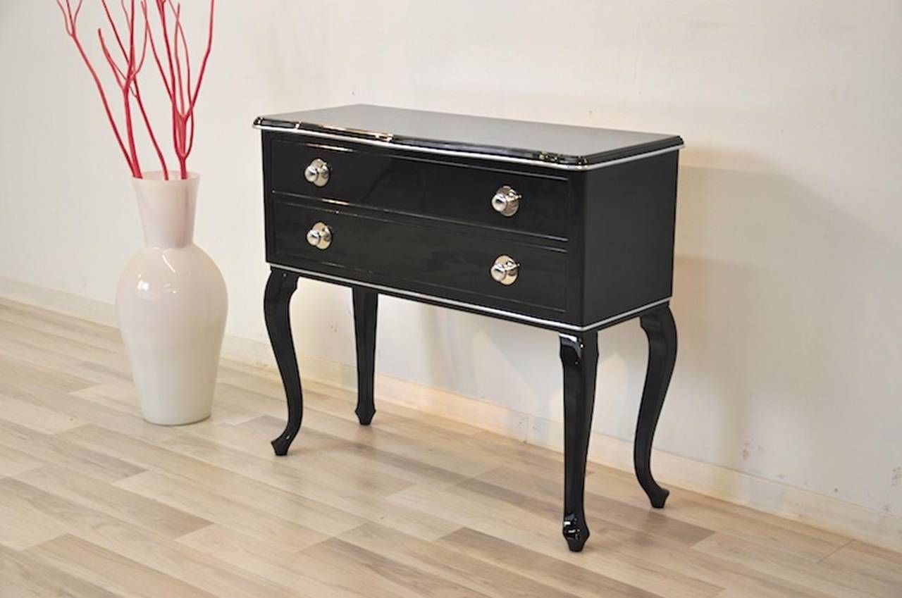 Petite Art Deco commode with wonderfully carved feet and two big drawers. Refined with fine chrome bars and our signature black high gloss lacquer. On the front you will also find 4 chrome knobs. An absolute classic and beautiful furniture!