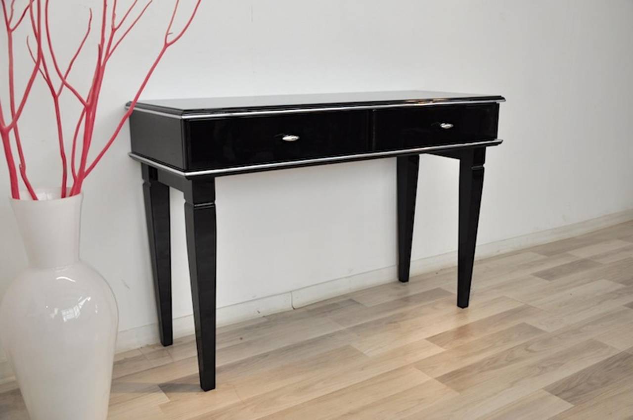 Art Deco style console table with filigree pointing feet and a high gloss black finish. With two drawers for storage and a beautiful paintjob. Also available with a blackened glass plate for protection. Feel free to contact us.

