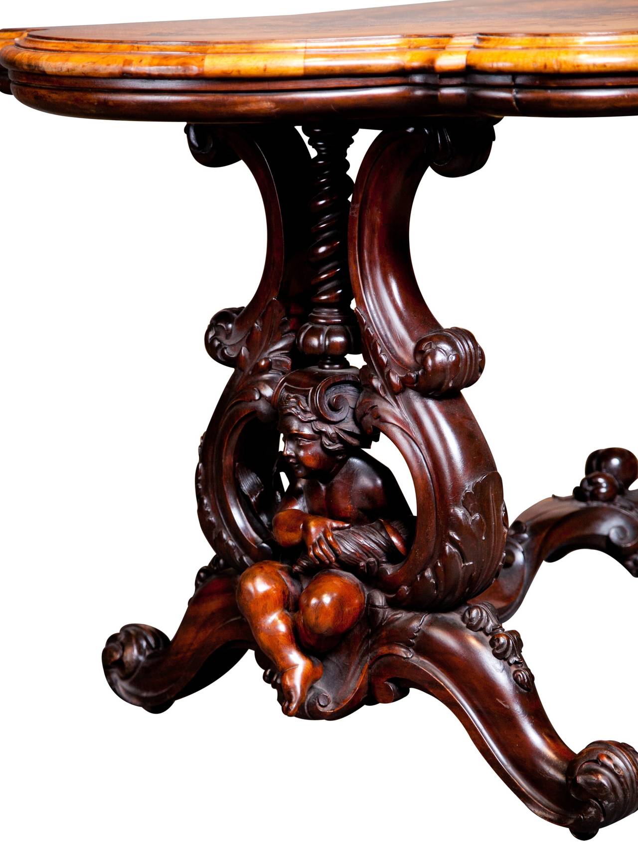 This exquisite, exhibition quality English center table was crafted in the manner of William Cookes of Warwick, England.

The table’s top is profusely inlaid with naturalistic forms and sits on a finely carved twin pedestal base displaying Putti