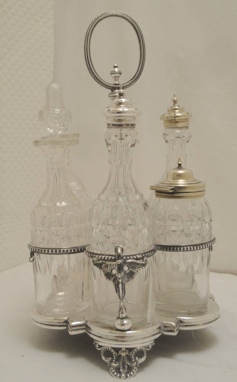 Silver plated cruet set.
Six cut-glass bottles see image 6 & 9.
Stamped with Victorian date mark indicating 20/07/1863.
No manufacturers mark. 
Slight plate wears on two of the tops slight chip to one of the bottle rims.