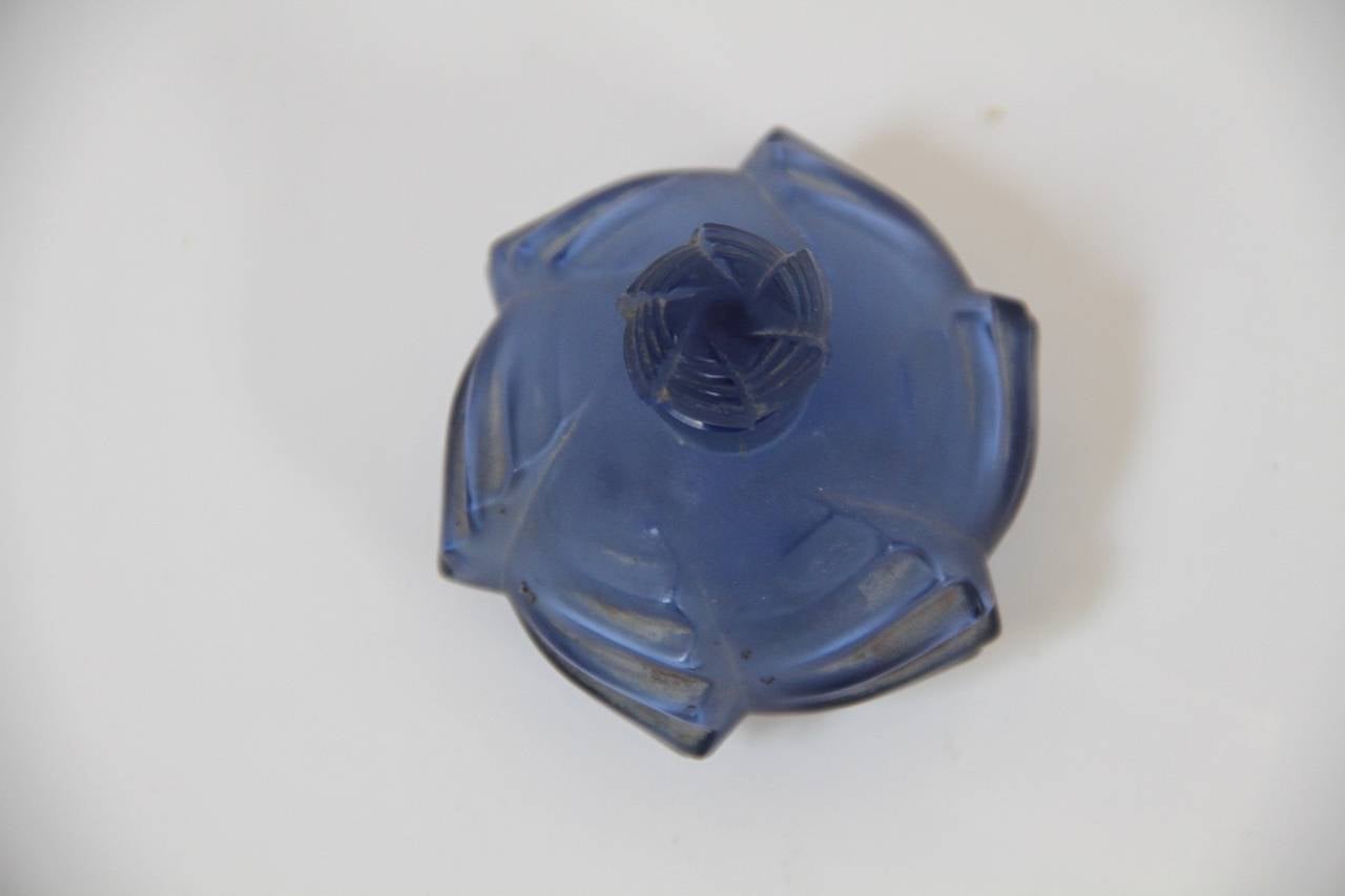 René Lalique glass Flacon Camille perfume bottle navy blue.
dit aussi flacon rond, bas, Torsades,
verre blanc souffle-moule patine et couleur, bouchon moule-presse,
haut 6cm,
figure aux catalogues de 1928 et de 1932,
supprime du catalogue en
