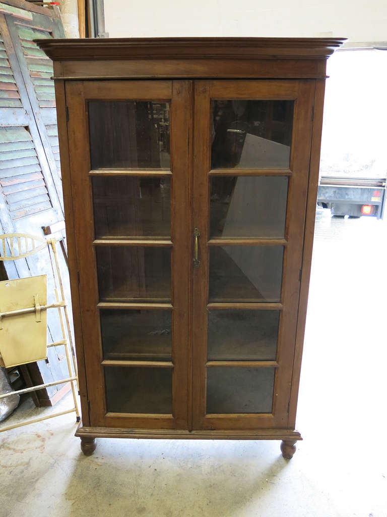 This is a Burmese teak bookcase or china cabinet from the early part of the 20th Century.  Inside are lots of shelves.  The patina on the sides of the piece are a lovely soft faded colour.