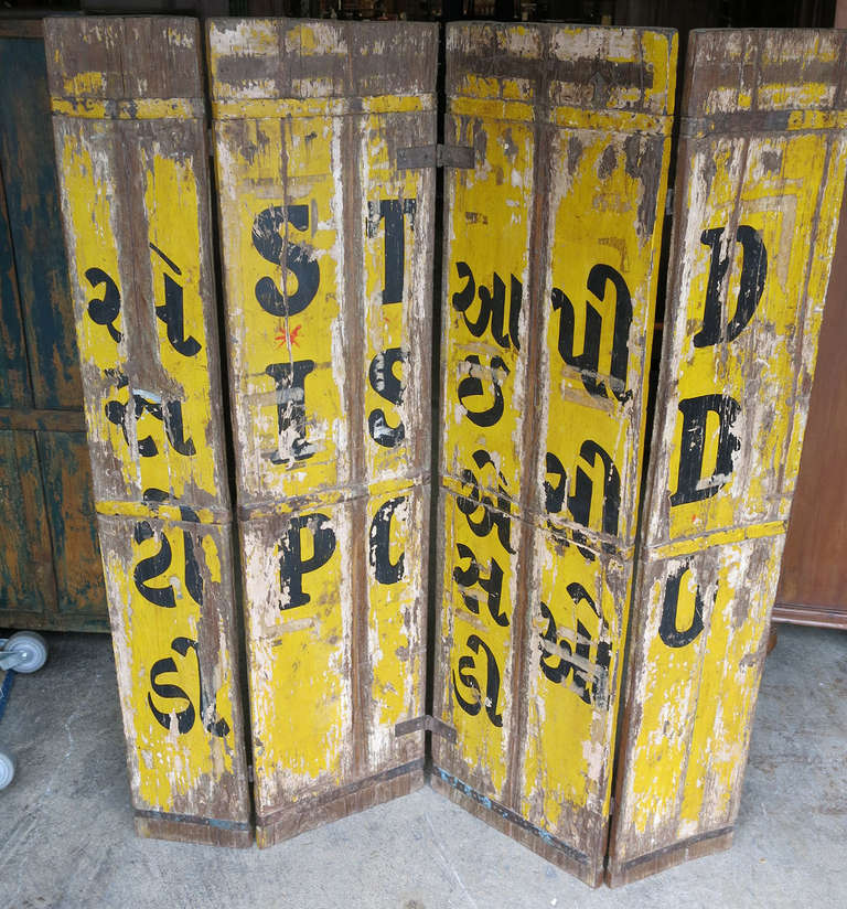 This is teak sign board with a great yellow background and black lettering hinged with four boards and detailed on both sides.  We honestly don't have any idea what it says but it sure looks great.