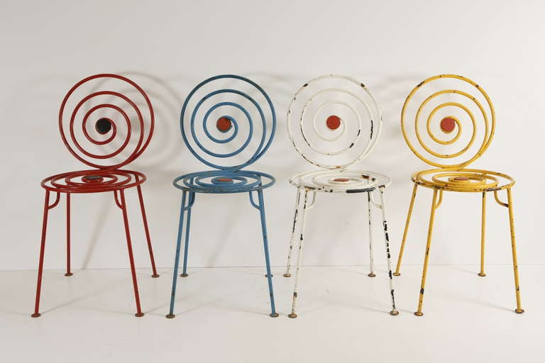 A set of four mid-century cast iron bistro chairs in red, blue, white, and yellow. Features deco-style spiraled backs and seats; suitable as garden chairs.
Made in France, c. 1950.