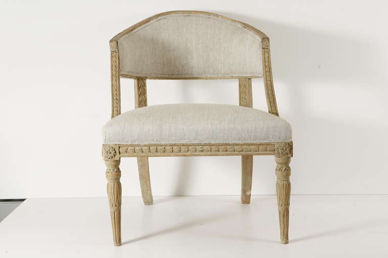 a pair of carved wood upholstered barrel-back gustavian armchairs.