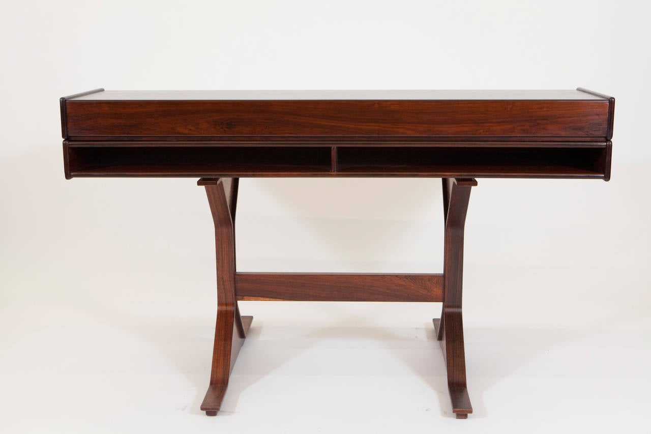 A beautiful Midcentury rosewood writing desk by an Italian design icon, Gianfranco Frattini for Bernini was made in Italy in 1957. This sleek proportioned desk is model 530 and features two drawers and a storage compartment on the front side with