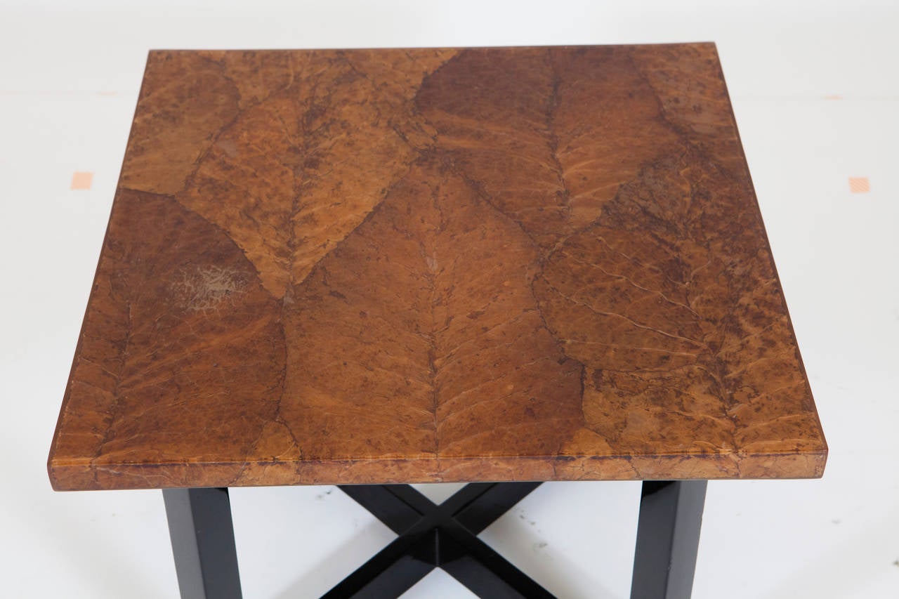 A low coffee or end table with laminated leaf pattern design and black lacquered legs.  