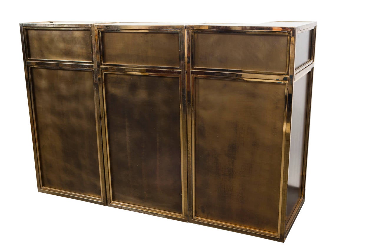 A very striking and rare three section brass-paneled bar unit with three matching stools attributed to Maison Romeo Rega. Inside the bar stand are shelves for placing bottles and barware. All three sections have front panels with the third having a