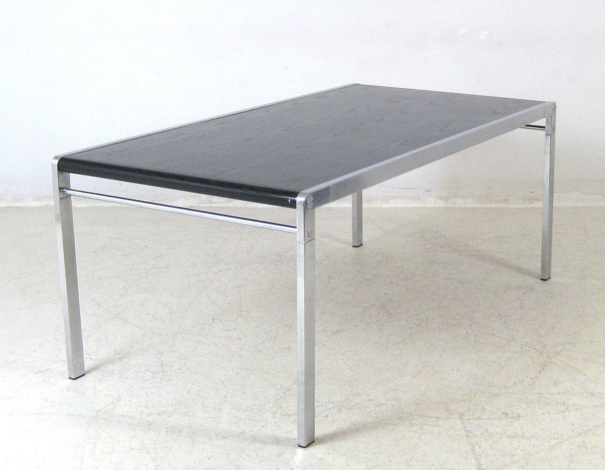 Ein 1971 von Claire Bataille und Paul Ibens entworfener Esstisch, Modell Anvers TE21. Das Edelstahlgestell ist teilweise gebürstet, während das Furnier der Tischplatte in glänzendem Schwarz gehalten ist. Die Stühle in den Hauptbildern sind auch