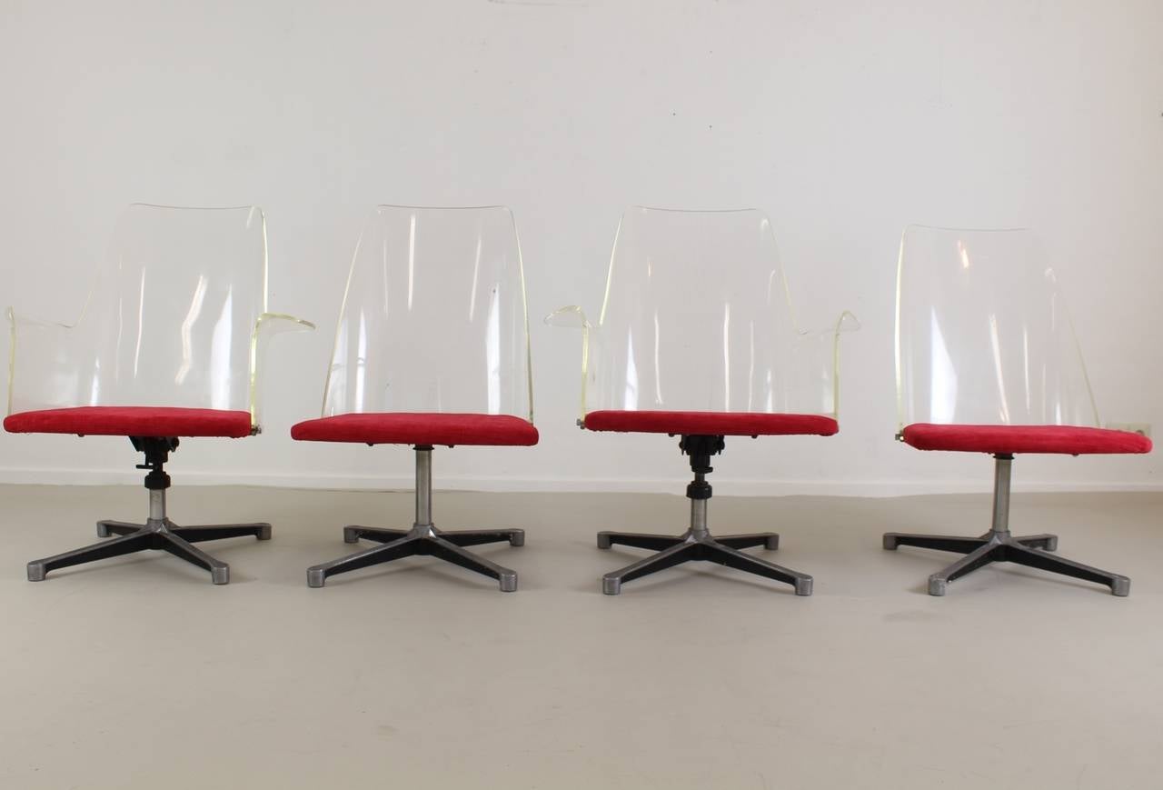 Typical American style, 1960s office chairs. Lucite back two chairs with all Lucite armrests. All revolving base. The chairs with armrest can tilt backwards. Reupholstered with red fabric. Also with loose red fabric cushions. Width of chairs without