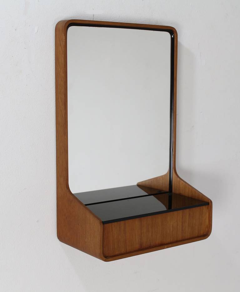 Friso Kramer designed for Auping bedroom furniture and also designed the beautiful plywood rounded wall mirror with storage. The glass plate (ribbed black safety glass) is flipped up to reach the small storage. The Euroika series by Friso Kramer for