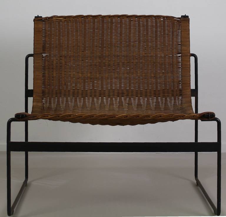 Delicate lightweight chair

Designers: Gregorio Vicente Cortes and Luis Onsurbe
Distributer in the Netherlands Metz & Co Amsterdam

Wicker backc and seating on a black metal base

With usermarks (a few canes are broken)
(a second chair