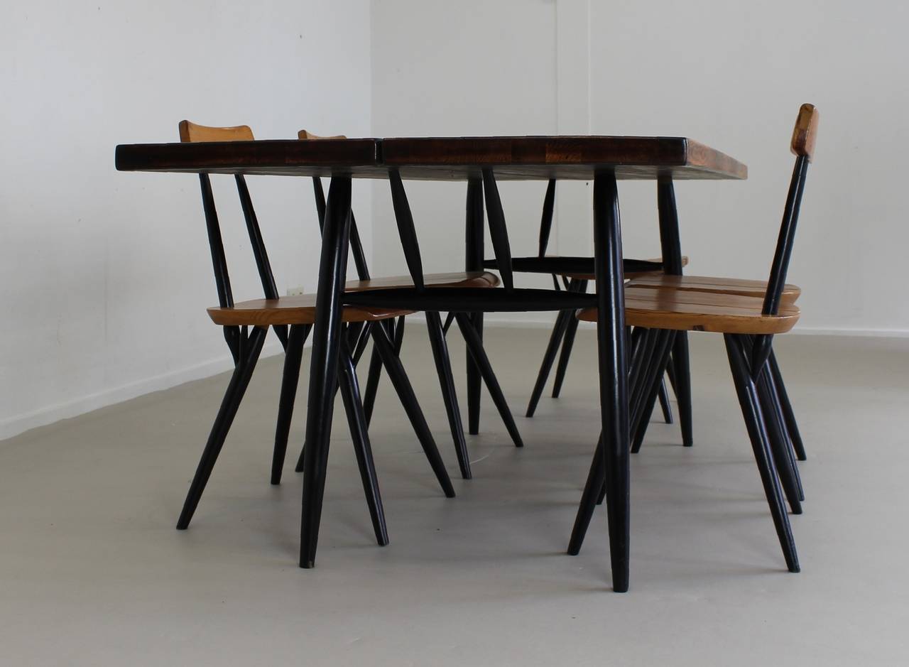 Dinnerset by wellknown Finnish designer Ilmari Tapiovaara
Set of four Pirkka chairs and large table
Extra Pirkka stool included
Manufacturer: Laukaan Puu Finland
Designed in 1955
Solid pinewood and black painted birchwood. 
Table size: H 70cm