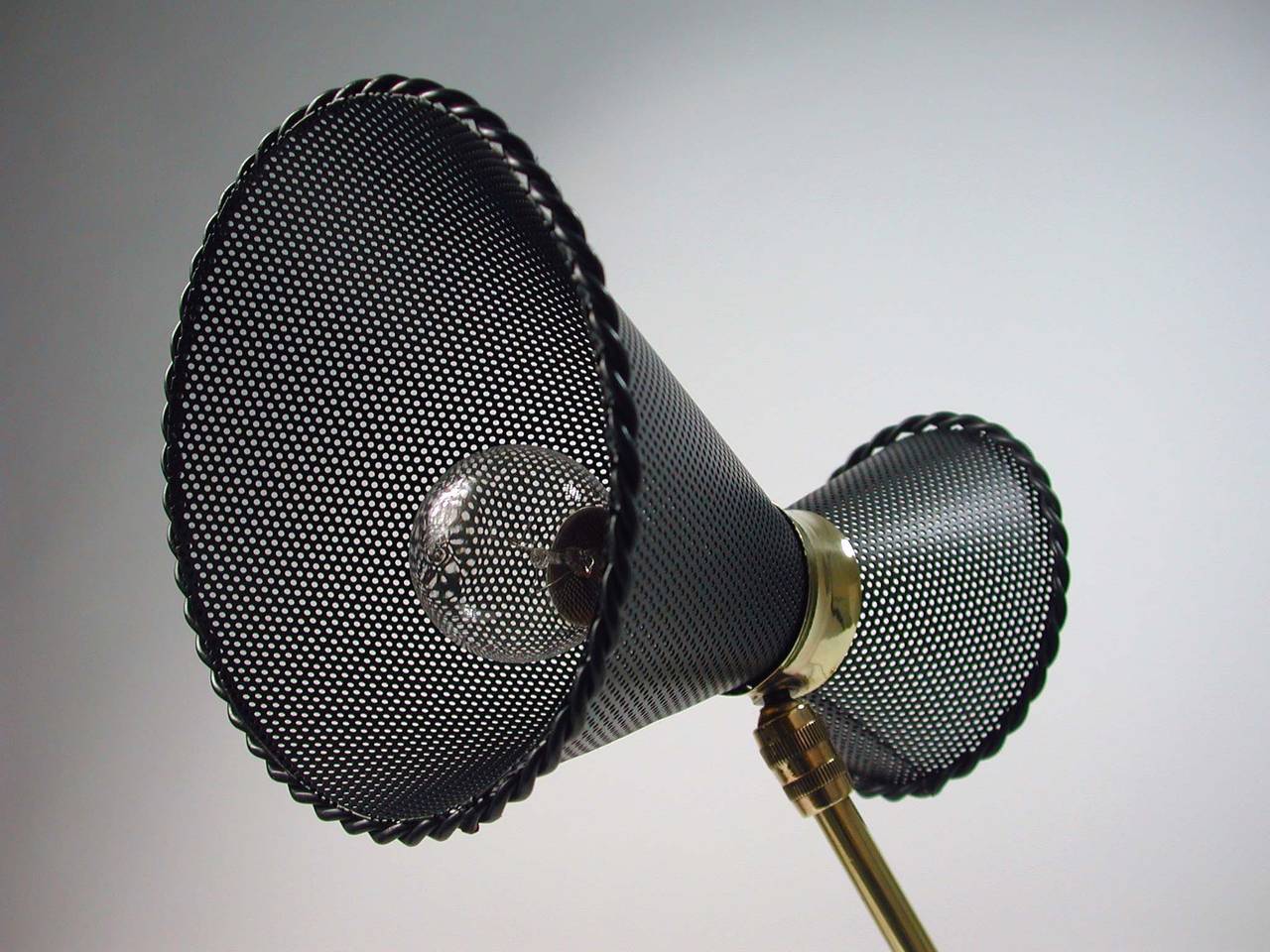 Very rare original Mathieu Mategot table lamp, made in France in the 1950s and manufactured by Atelier Mategot.
Brass lamp foot and rotatable dark grey lacquered perforated lamp shade.
The lamp has got a B22 bayonett socket and works on 110V as