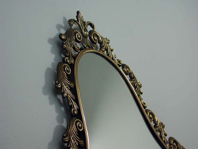 This beautiful wall mirror was designed and manufactured in Italy in the 1950s. It has got a shield  neoclassical bronze frame. Condition is very good. The mirror glass is new.