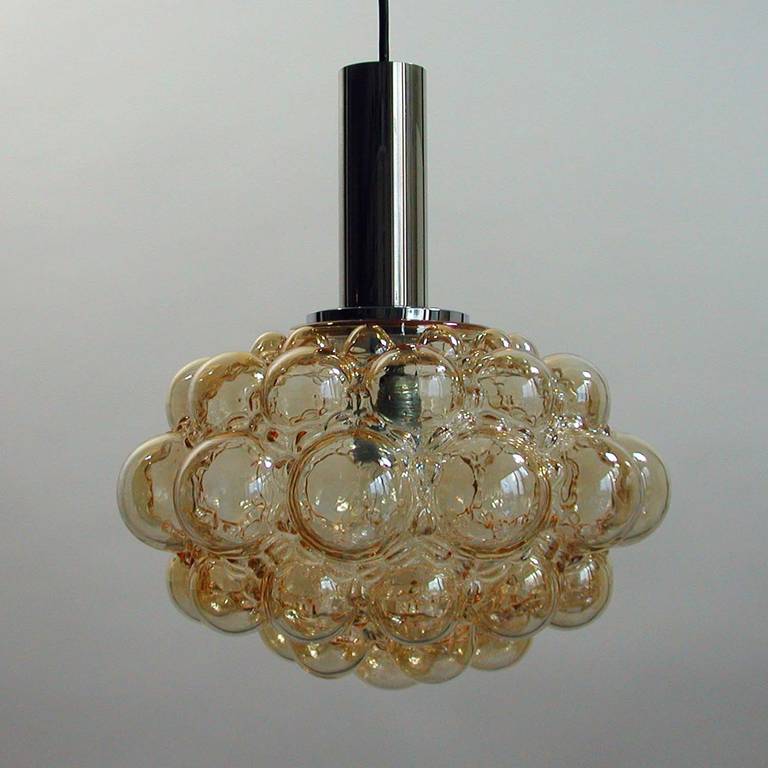 Late 1960s amber bubble and chrome pendant designed in the 1960s by Helena Tynell and Heinrich Gatenbrink for Glashuttenwerke Limburg, Germany.

The lampshade is made of glass with an amber tinge and a bubble pattern. On top of the lampshade there