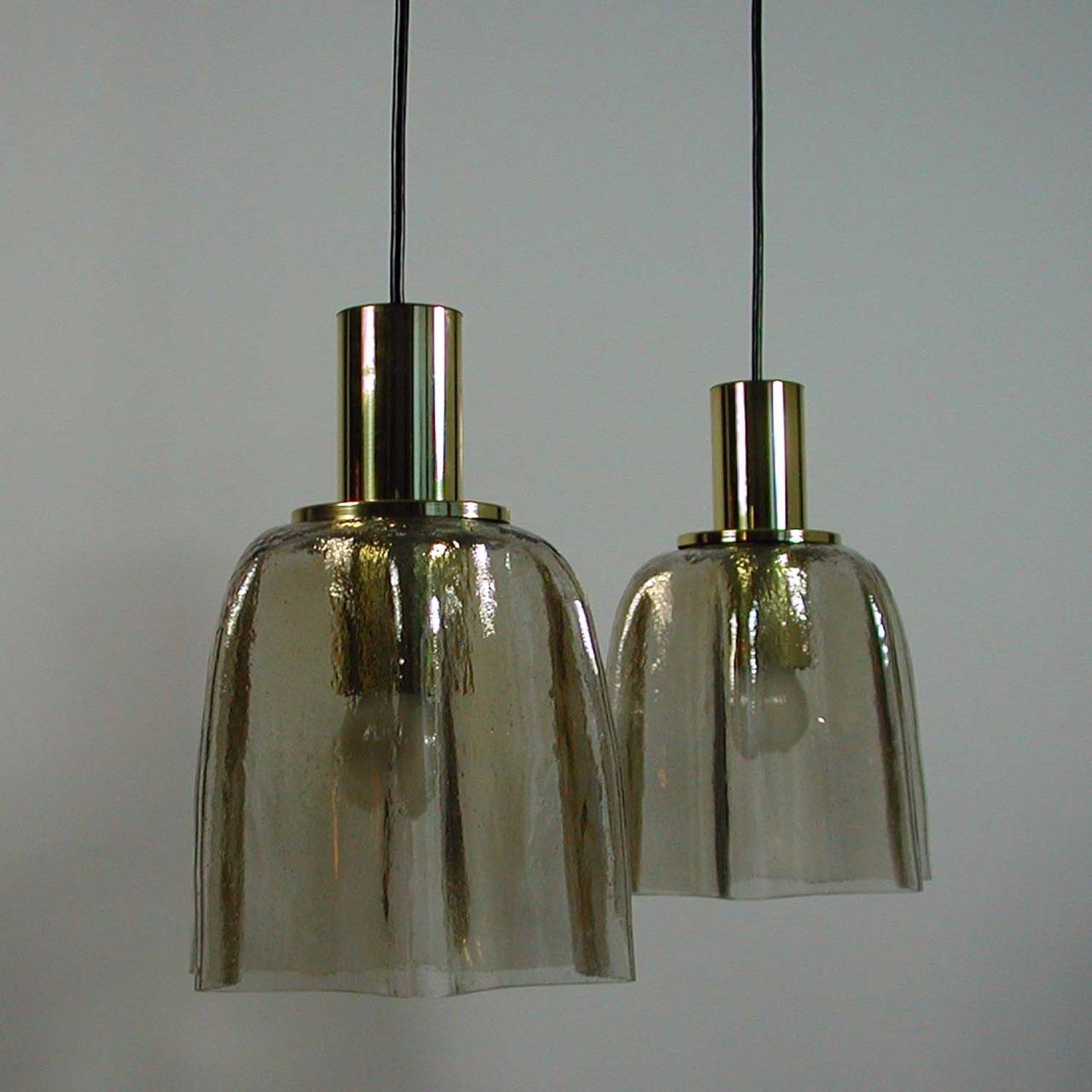 Awesome tinted amber handkerchief ice glass and brass pendant by Limburg. Manufactured in Germany in the 1960s.

The lamp has got a E27 screw on socket each. The glass shade is topped by a brass cylinder.

Measures: Total height with wiring is 52