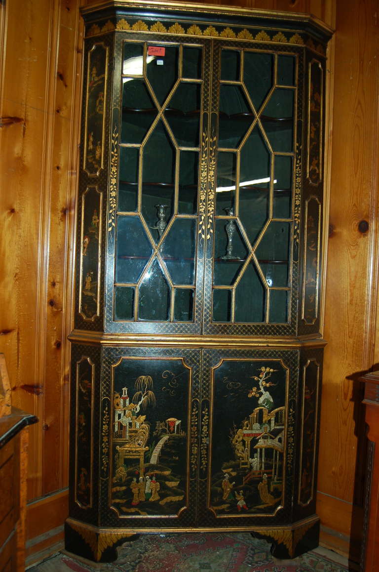 English corner cabinet, made circa 1780, in lacquered gilt chinoisoire. Stunningly beautiful lacquered gilt chinoisoire on a black ground. Bracket feet to the base. 13 pane astrical glazed glass in the upper doors. Nice old wavy glass. Three