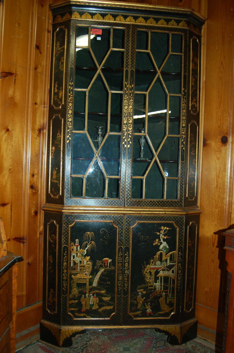 English corner cabinet, made circa 1780, in lacquered gilt chinoisoire. Stunningly beautiful lacquered gilt chinoisoire on a black ground. Bracket feet to the base. 13 pane astrical glazed glass in the upper doors. Nice old wavy glass. Three