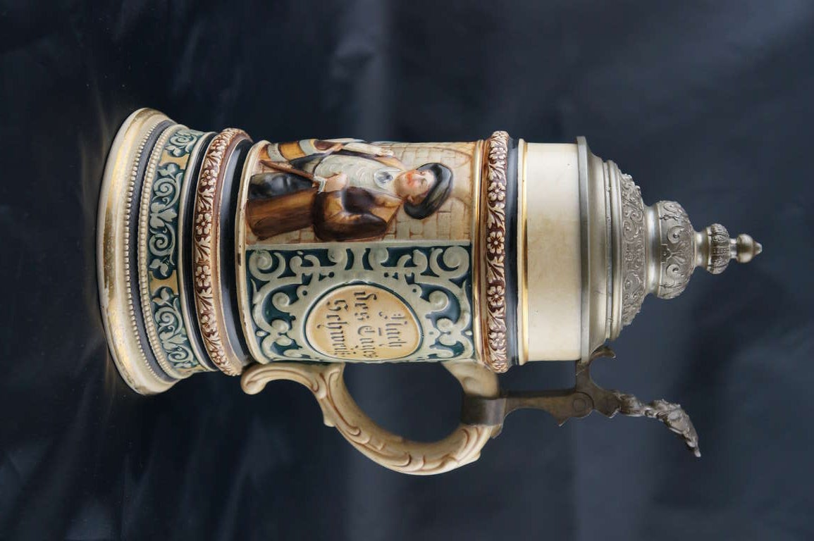 A Germany Stein, polychrome decorated with typical beer drinkers. One of the persons is smoking a pipe and the others enjoy their beer at the Münchner Hofbräuhaus